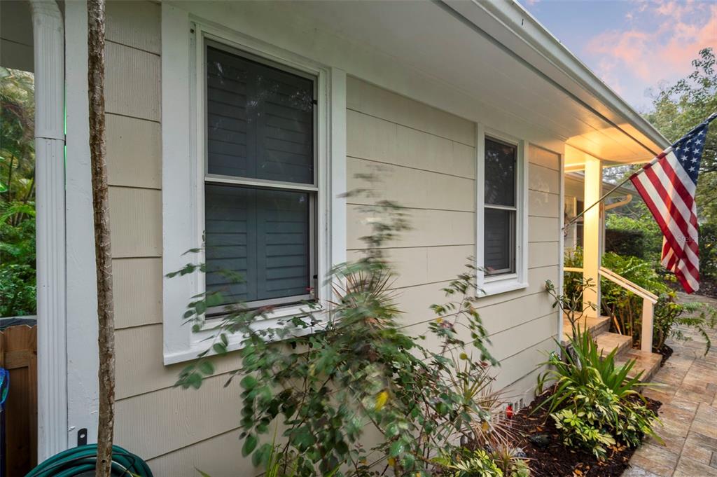 The exterior of a beige house features horizontal siding, two windows, and an American flag — 501 BROADWAY, DUNEDIN, FL