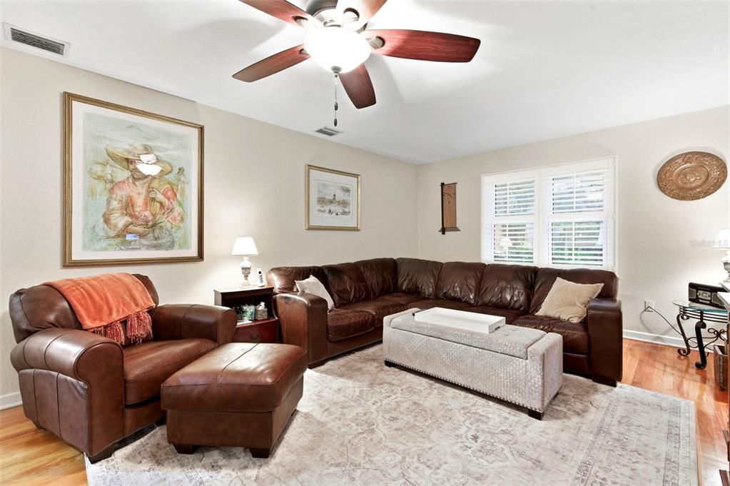 A living room features a brown leather sectional, a matching armchair with ottoman, and hardwood floors — 501 BROADWAY, DUNEDIN, FL