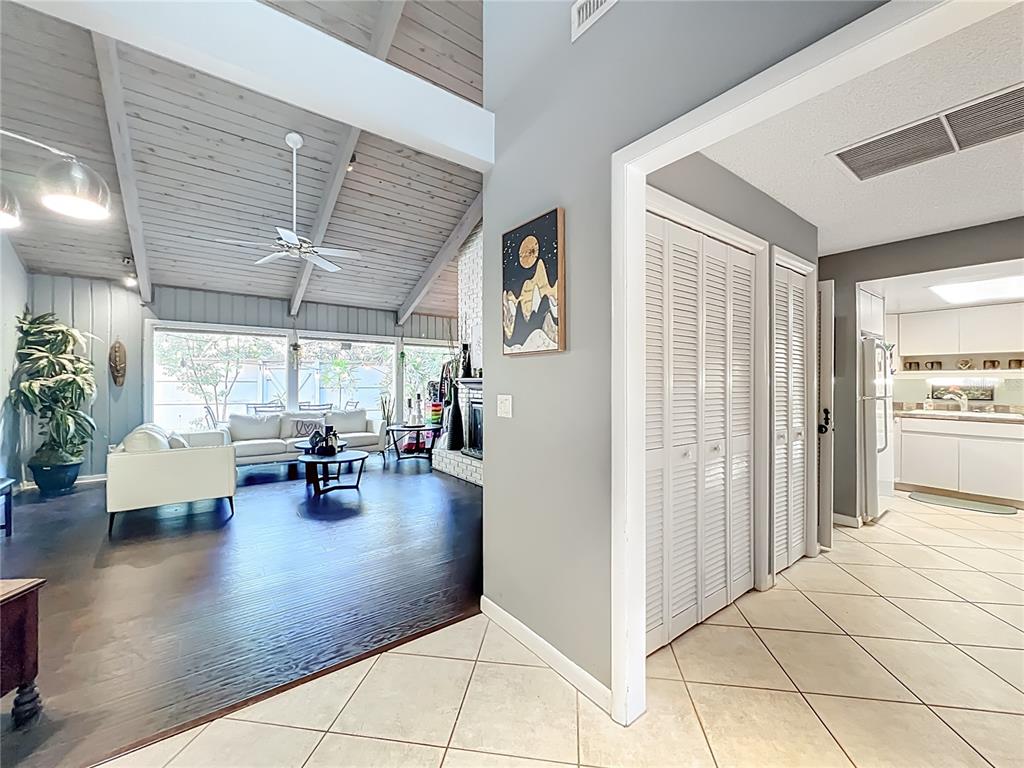 A living room with vaulted ceilings and dark wood floors connects to a tiled kitchen — 104 JUNIPER LANE, LONGWOOD, FL