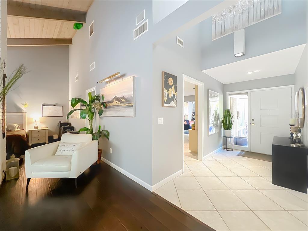 An entryway with tile flooring leads to a living area featuring dark wood floors — 104 JUNIPER LANE, LONGWOOD, FL