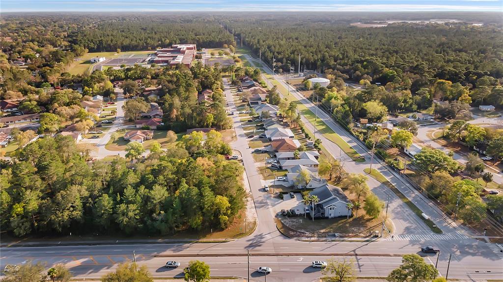 An aerial view shows a residential neighborhood with houses, trees, and a main road — 4380 AZORA ROAD, SPRING HILL, FL