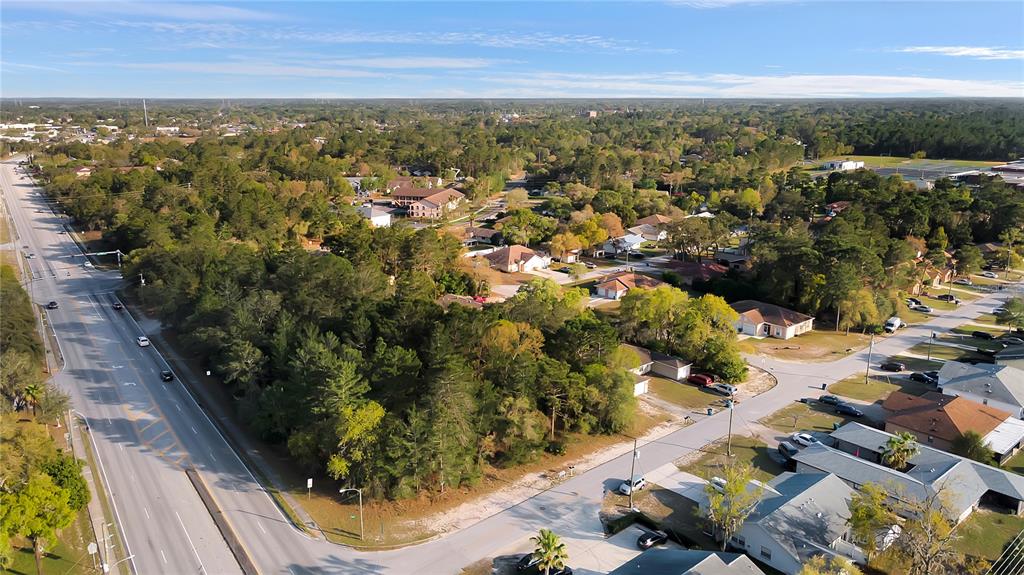 An aerial view shows a wooded lot situated between a multi-lane road and residential houses — 4380 AZORA ROAD, SPRING HILL, FL