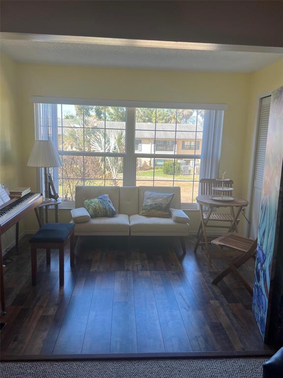 A sunlit room features a small sofa, a piano, a wooden table, and wood-look flooring — 110 N TREMAIN STREET UNIT 110, MOUNT DORA, FL