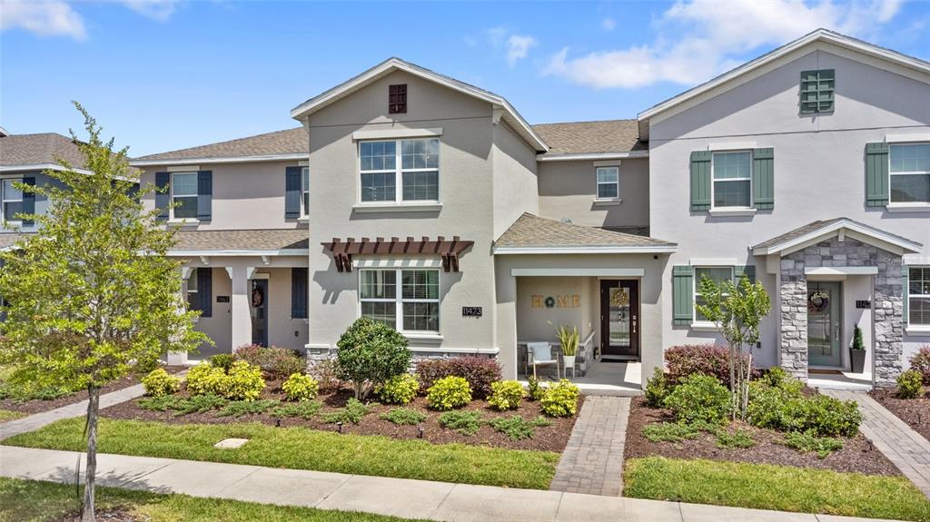 A multi-unit residential building features stucco siding, stone accents, and front-facing entryways with walkways — 11473 LISTENING DRIVE, ORLANDO, FL
