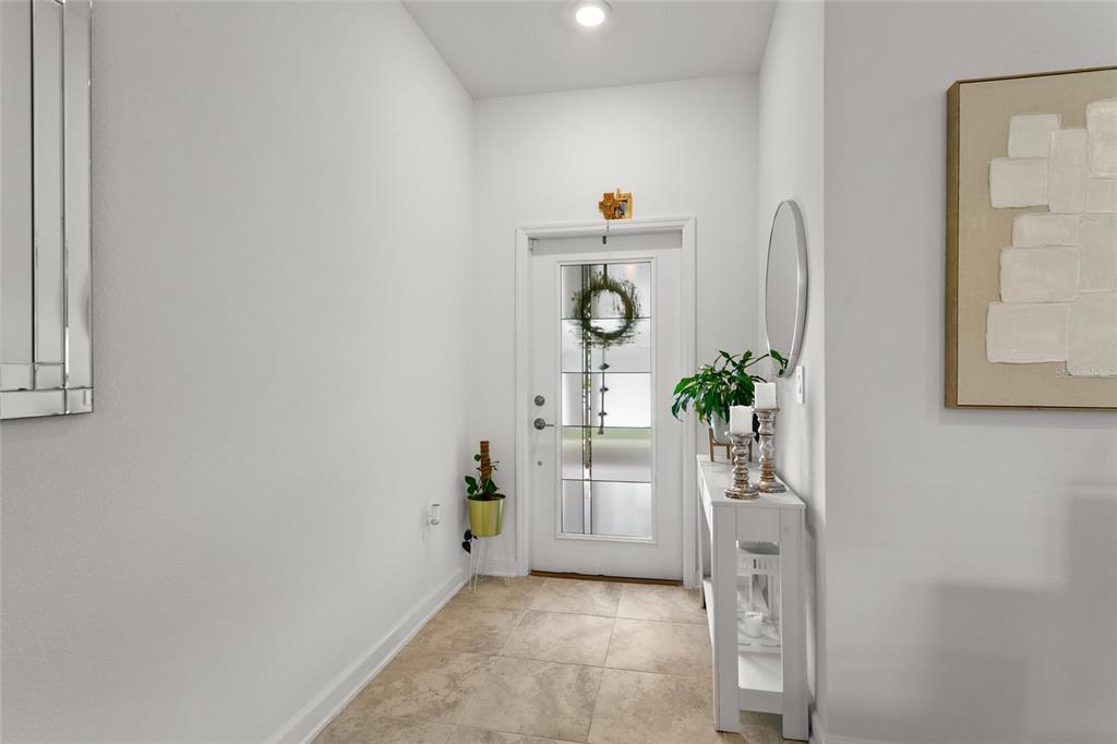 A bright entryway features tile flooring, a white front door with glass panels, and console table — 11473 LISTENING DRIVE, ORLANDO, FL