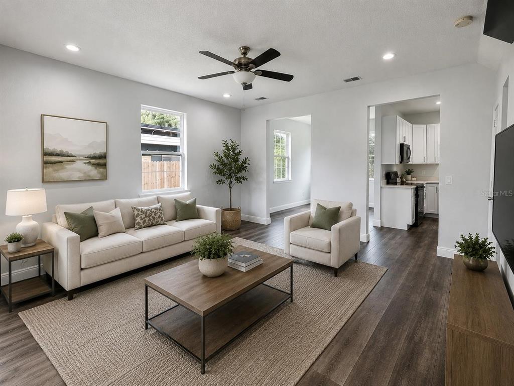 A living room with light walls, gray wood-look flooring, a white sofa, and a staircase — 3778 MARTIN STREET, ORLANDO, FL