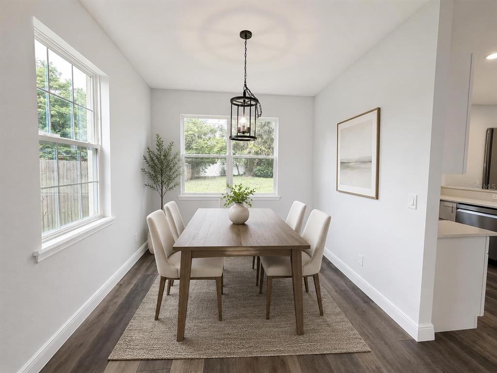 A living room with gray wood-look flooring, a ceiling fan, and an adjacent kitchen area — 3778 MARTIN STREET, ORLANDO, FL