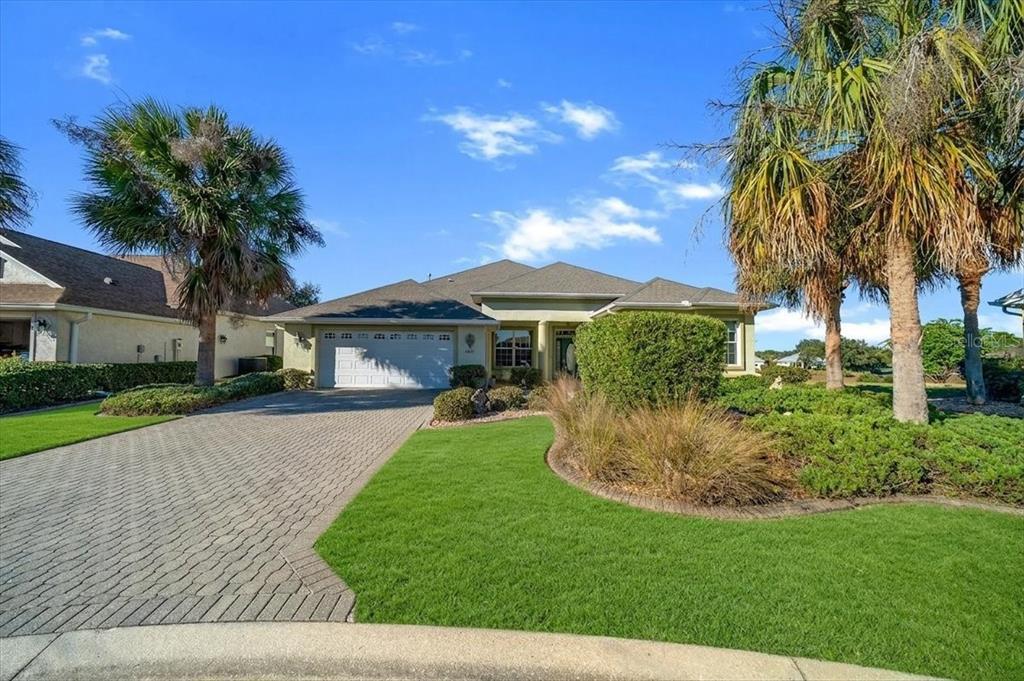 A single-story house with a paved driveway, green lawn, and palm trees under a blue sky — 8459 SW 84TH LOOP, OCALA, FL
