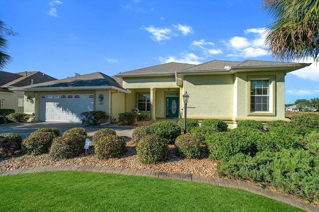 A single-story house with a light-colored stucco exterior, a two-car garage, and landscaped front yard — 8459 SW 84TH LOOP, OCALA, FL