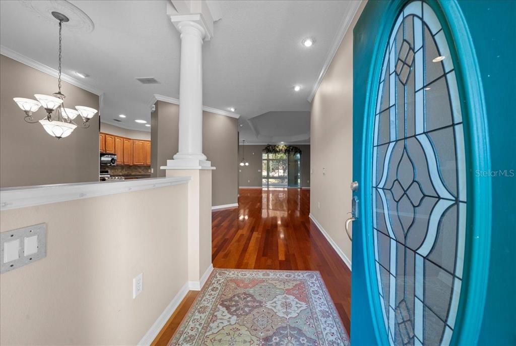 An entryway with hardwood floors, a decorative teal door, and a white column — 8459 SW 84TH LOOP, OCALA, FL