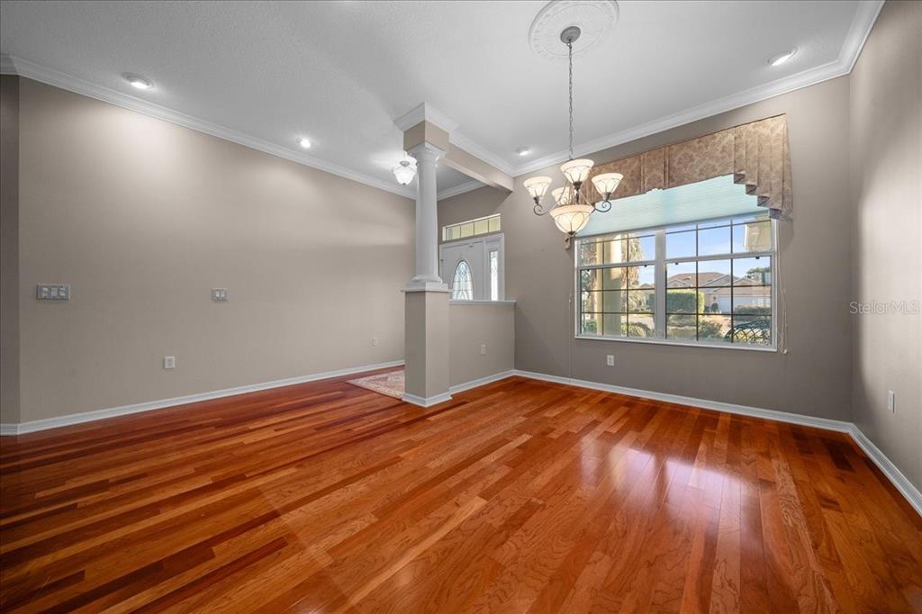 A dining room features hardwood floors, a central column, and a chandelier over a window — 8459 SW 84TH LOOP, OCALA, FL