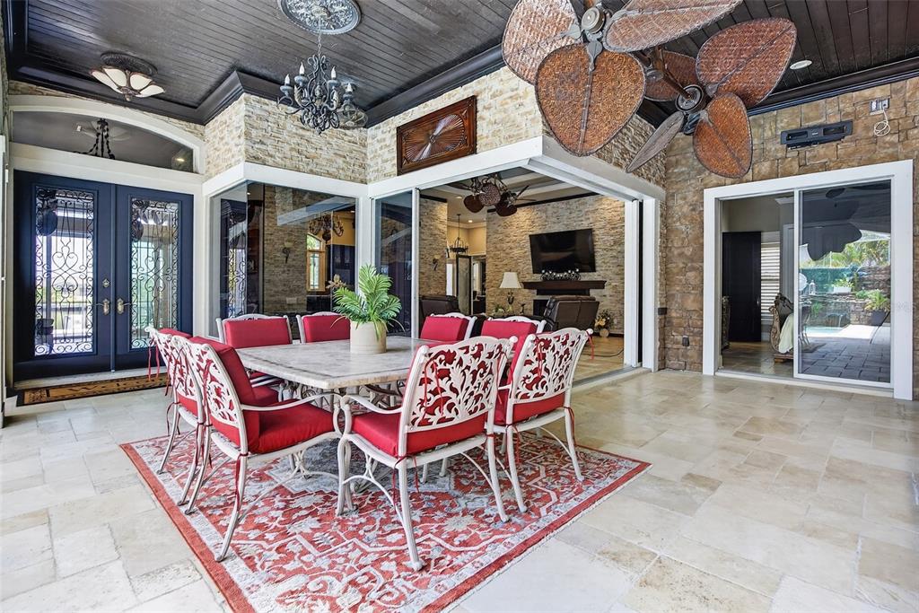 A covered outdoor dining area features stone walls, a dark wood ceiling, and red chairs — 3866 TURTLE DOVE BOULEVARD, PUNTA GORDA, FL