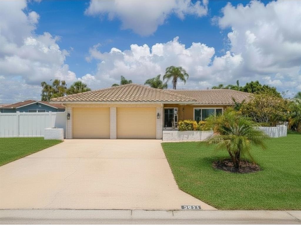 A single-story house with a two-car garage, tile roof, and a front lawn — 5011 ENSIGN LOOP, NEW PORT RICHEY, FL