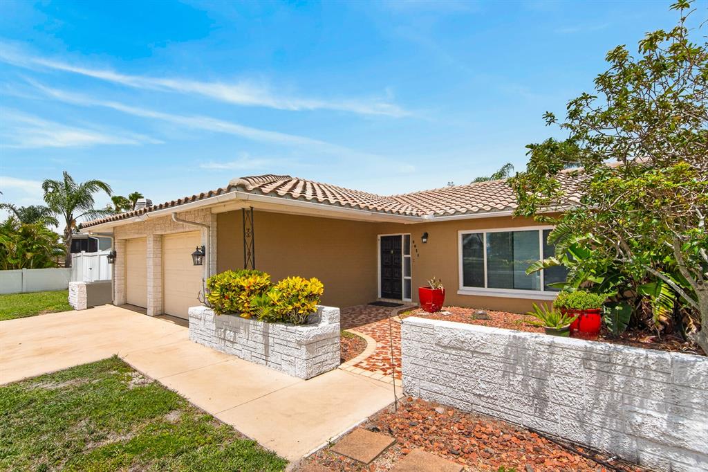 A single-story house with a tan exterior, tiled roof, two-car garage, and a brick walkway — 5011 ENSIGN LOOP, NEW PORT RICHEY, FL