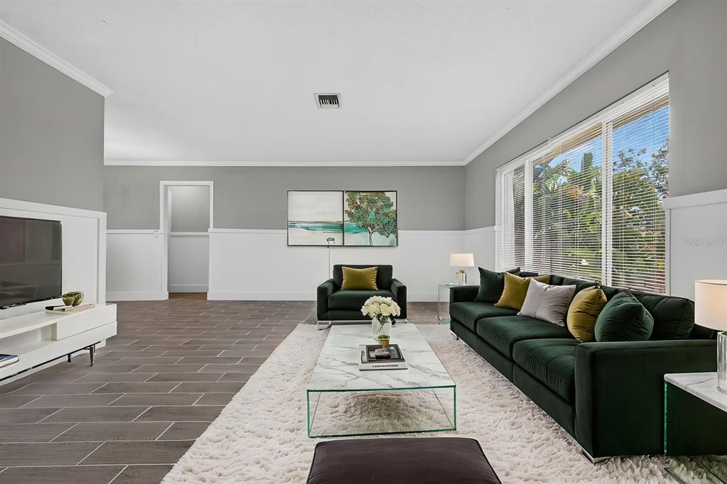 A living room features gray walls, white wainscoting, a dark green sofa, and tile flooring — 5011 ENSIGN LOOP, NEW PORT RICHEY, FL