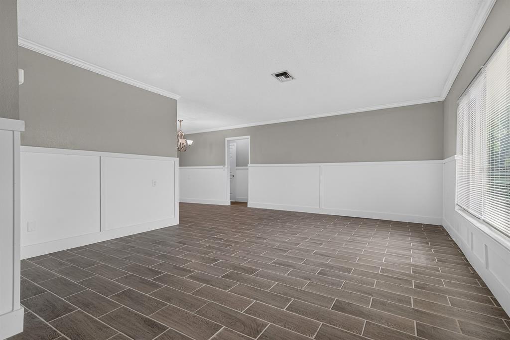 An empty room features gray walls, white wainscoting, and dark wood-look tile flooring — 5011 ENSIGN LOOP, NEW PORT RICHEY, FL