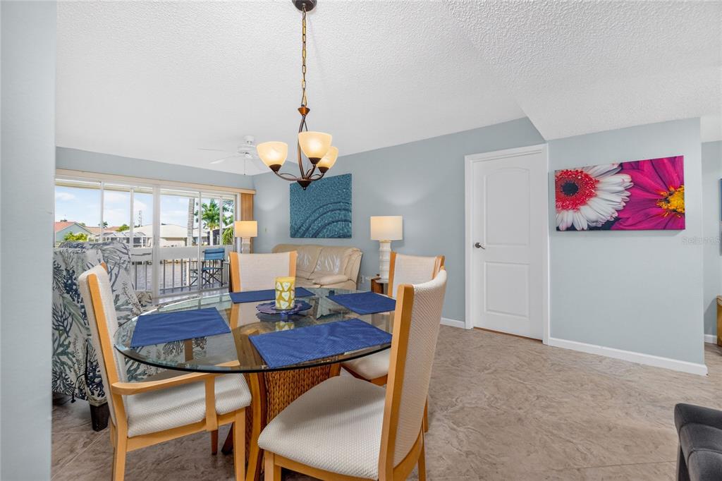 A dining area features a glass-topped table, four chairs, a chandelier, and a sliding glass door — 1080 BAL HARBOR BOULEVARD UNIT 7C, PUNTA GORDA, FL