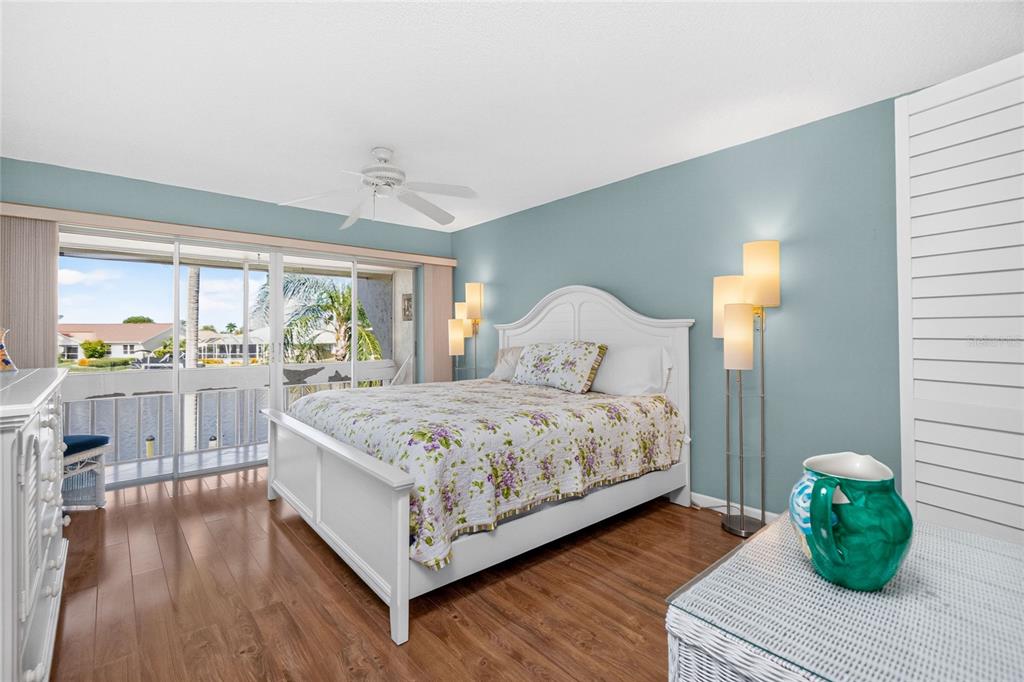 A bedroom features a white bed with floral bedding, blue walls, and a sliding glass door — 1080 BAL HARBOR BOULEVARD UNIT 7C, PUNTA GORDA, FL