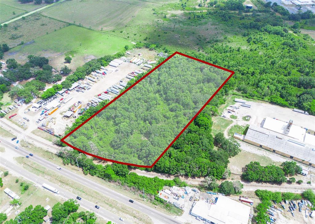 An aerial view shows a rectangular, wooded lot outlined in red next to industrial properties — SR-60, LAKE WALES, FL