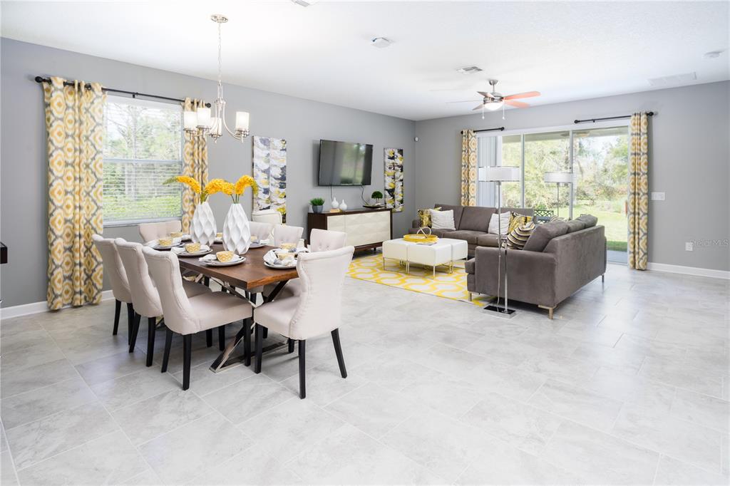 An open-concept living and dining room with gray walls, tile flooring, and yellow patterned accents — 2220 BARRINGTON LOOP, DAVENPORT, FL