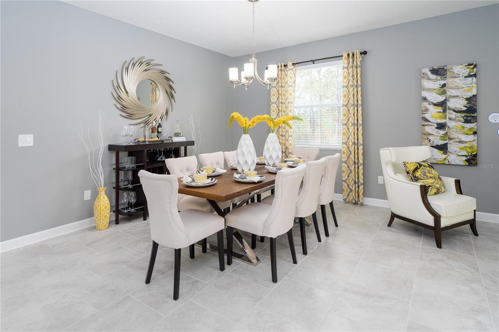 A dining room features a wooden table, upholstered chairs, a bar console, and yellow accents — 2220 BARRINGTON LOOP, DAVENPORT, FL