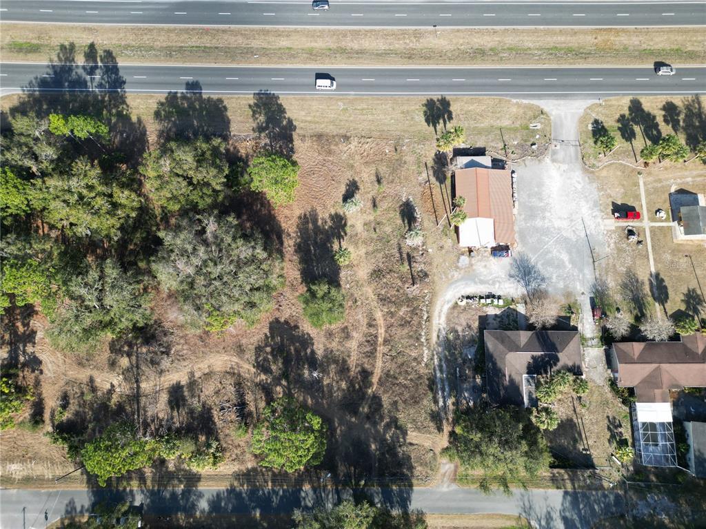 An aerial view shows a vacant lot situated between a highway and residential properties — 12441 SE 72ND AVENUE, BELLEVIEW, FL