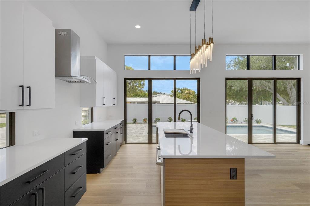 A modern kitchen with a large island, two-tone cabinetry, and views of a backyard pool — 2079 HIBISCUS STREET, SARASOTA, FL
