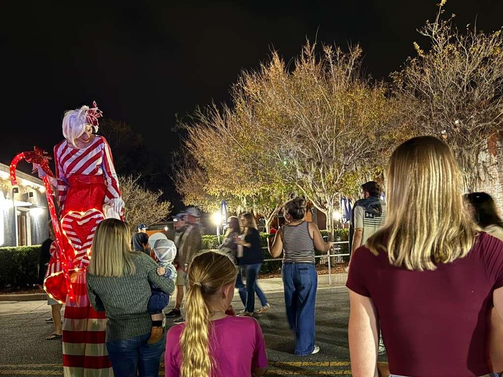 A stilt walker in a candy cane costume interacts with a crowd at night — 7756 N SHILLELAGH AVENUE, CRYSTAL RIVER, FL