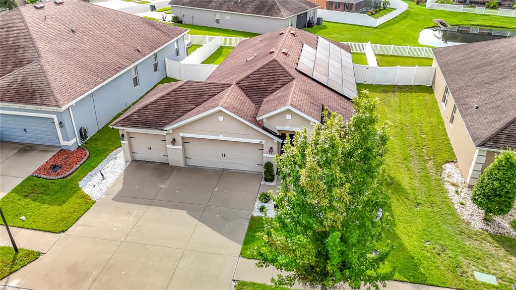 An aerial view shows a single-story house with a tan exterior, solar panels, and driveway — 6328 SPARKLING WAY, WESLEY CHAPEL, FL