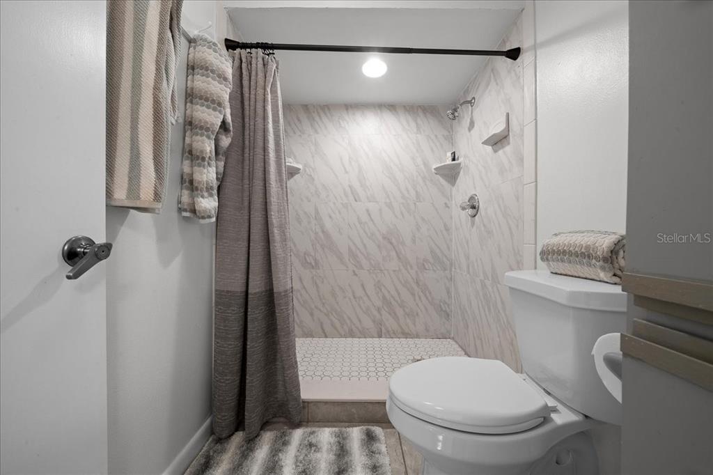 A bathroom features a walk-in shower with marble-look tile and a white toilet — 2925 N RIVERS EDGE BOULEVARD UNIT 2925, CRYSTAL RIVER, FL
