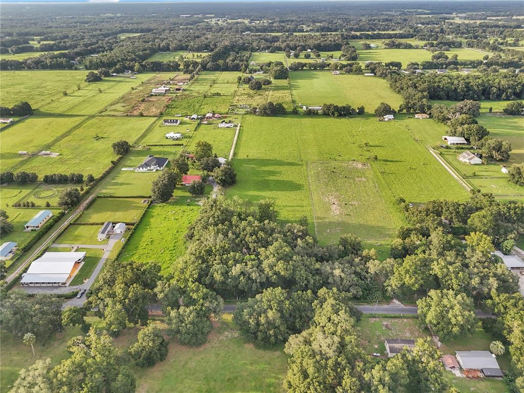 An aerial view shows multiple rural properties with houses, barns, and pastures surrounded by trees — 000 SE 160TH STREET, SUMMERFIELD, FL