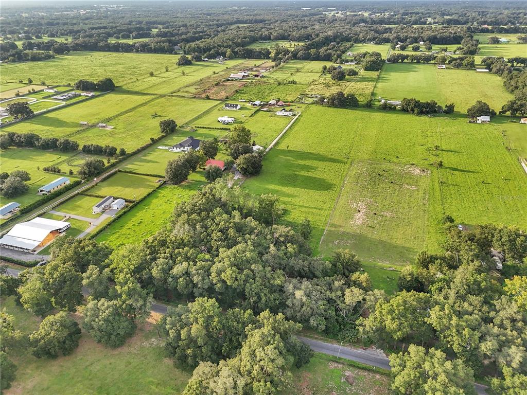 An aerial view shows a rural landscape with pastures, scattered houses, and dense tree clusters — 000 SE 160TH STREET, SUMMERFIELD, FL