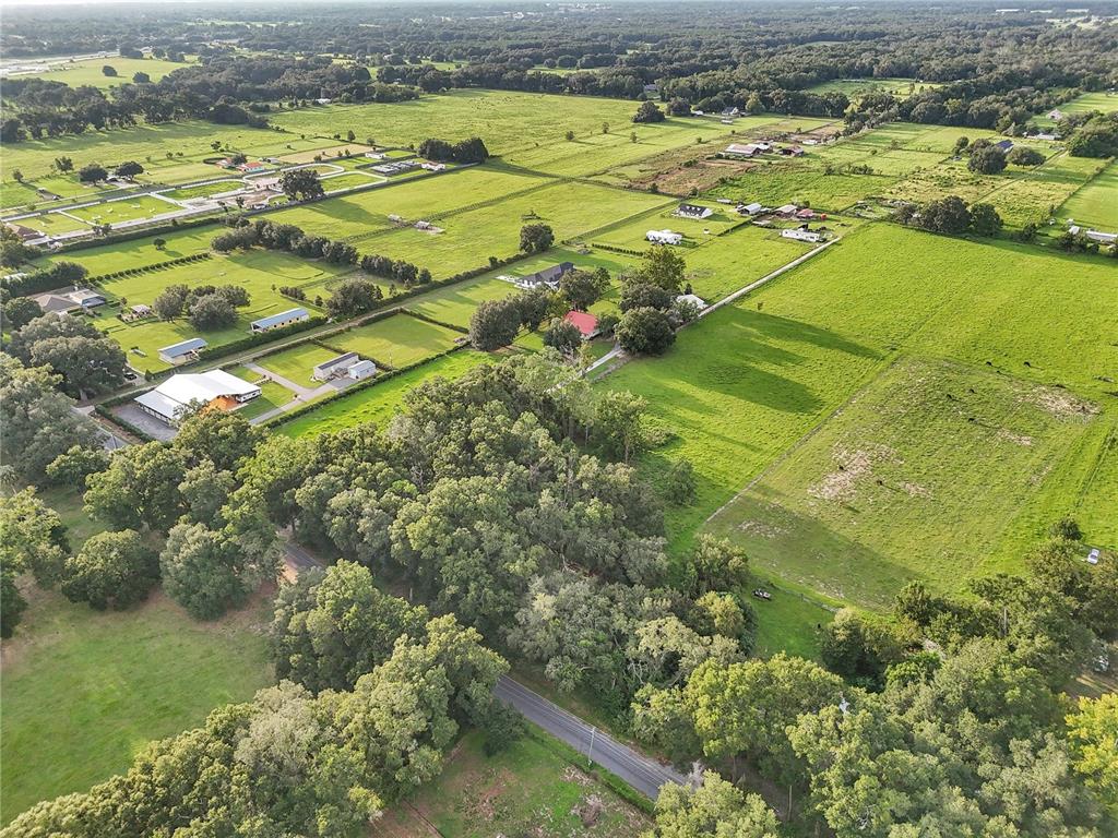 An aerial view shows a rural landscape with pastures, scattered houses, and dense tree clusters — 000 SE 160TH STREET, SUMMERFIELD, FL