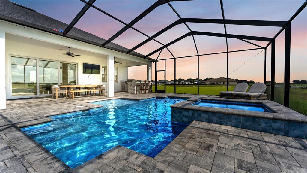 A screened-in patio features a swimming pool, a hot tub, and an outdoor dining area — 7034 BENTRIDGE DRIVE, LAKELAND, FL