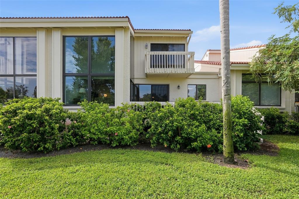 The exterior of a two-story residential building features large windows, a balcony, and landscaping — 5619 ESCONDIDA BOULEVARD S, ST PETERSBURG, FL