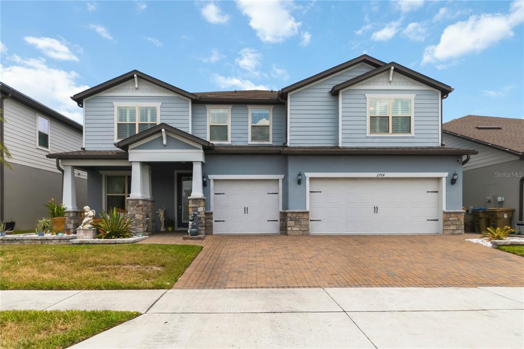 A two-story suburban house with a blue exterior, stone accents, and a three-car garage — 2764 MATERA DRIVE, ST CLOUD, FL