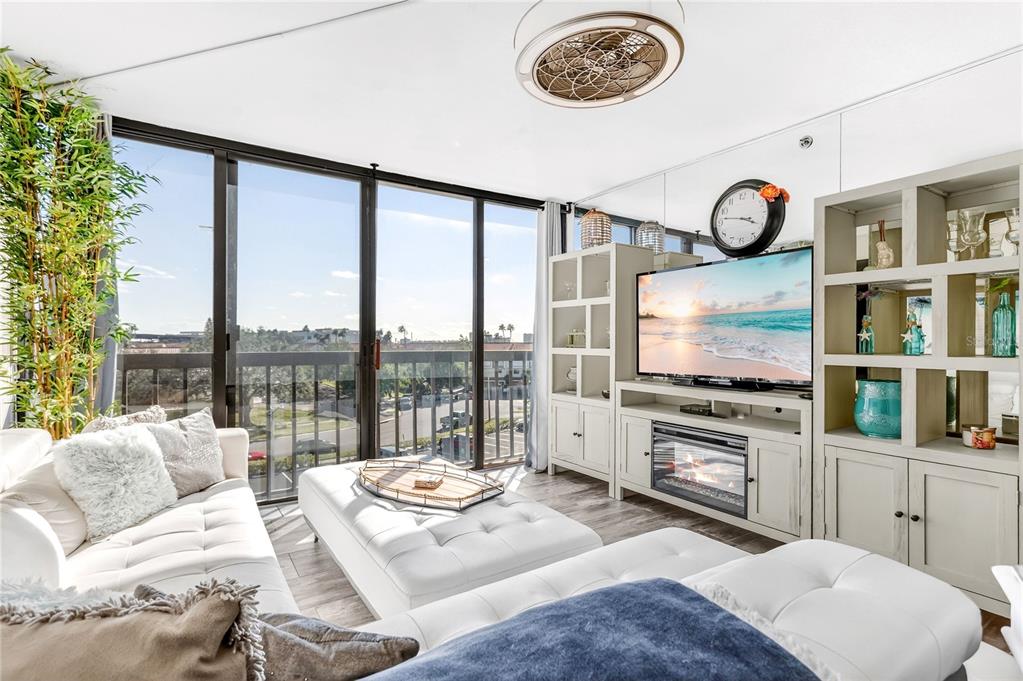 A living room features a white sofa, a large ottoman, and a wall-mounted television — 255 DOLPHIN POINT UNIT 407, CLEARWATER BEACH, FL
