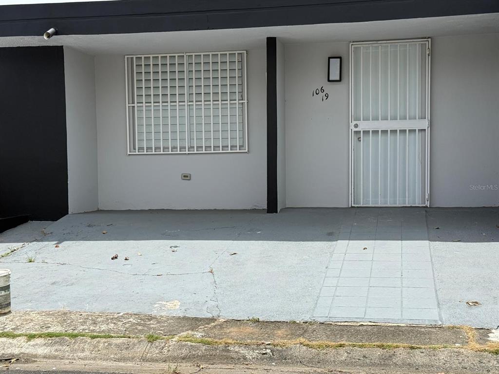 A gray exterior view of a house with a security gate and window bars — VILLA CAROLINA CALLE 102 UNIT 106-19, CAROLINA, PR