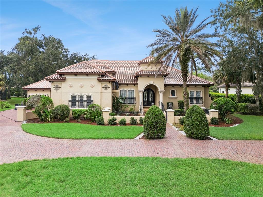 A single-story stucco house with a tile roof, arched entryway, and a brick driveway — 7764 ISLEWOOD COURT, SANFORD, FL