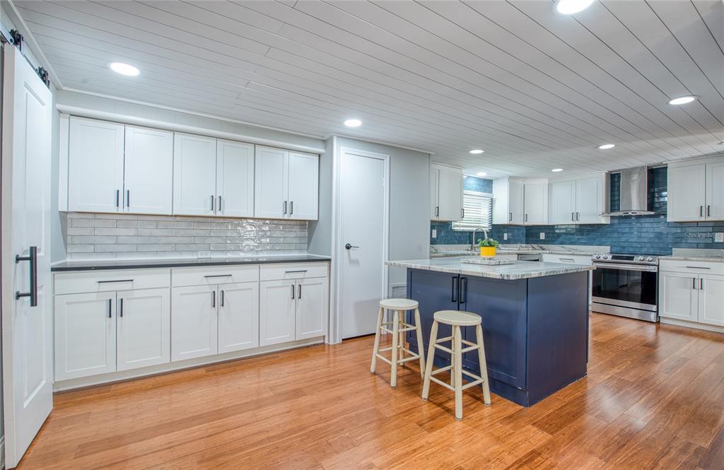 A kitchen with white cabinets, a blue island, wood flooring, and a planked ceiling — 407 DOLPHIN DRIVE S, OLDSMAR, FL
