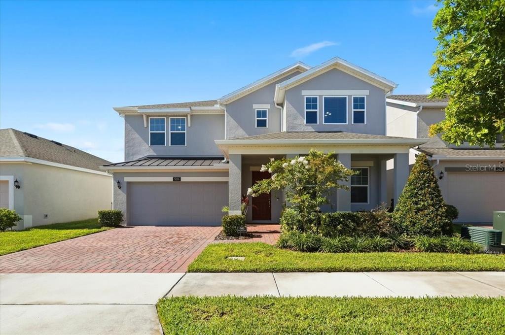 A two-story house with a gray stucco exterior, a red front door, and a brick driveway — 5026 DOWN COURT, ST CLOUD, FL