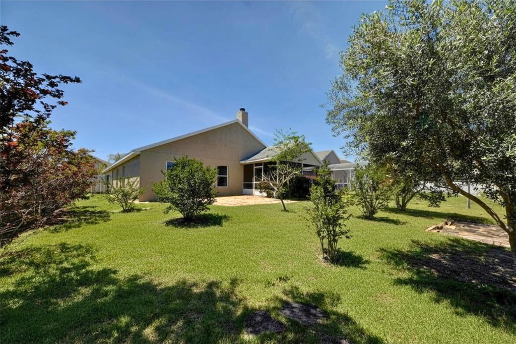 The exterior view shows the back of a house with a screened-in porch and lawn — 635 ROCHESTER LOOP, DAVENPORT, FL