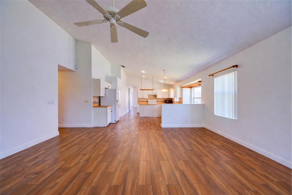 A spacious living area with wood-look tile flooring leads into an open-concept kitchen — 635 ROCHESTER LOOP, DAVENPORT, FL