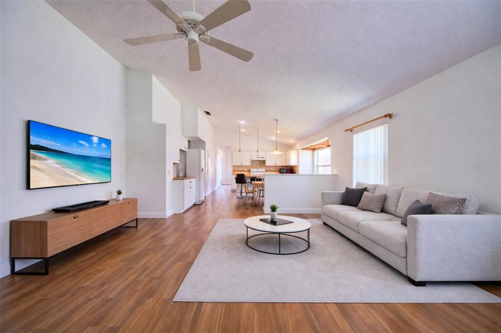 A living room with wood flooring, a white sofa, and a wall-mounted television — 635 ROCHESTER LOOP, DAVENPORT, FL