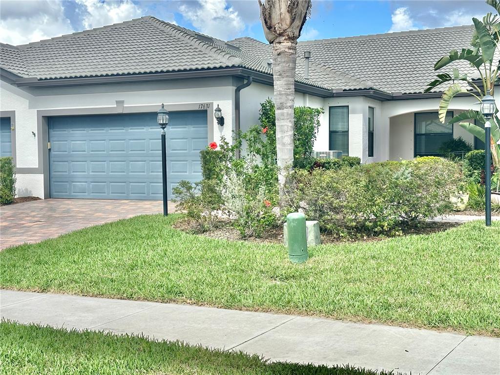 A single-story house with a blue garage door, a tiled roof, and a front lawn — 17631 CAMDEN DRIVE, BRADENTON, FL