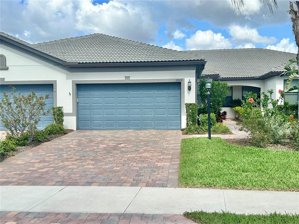 A single-story house features a blue garage door, a paved driveway, and a tiled roof — 17631 CAMDEN DRIVE, BRADENTON, FL