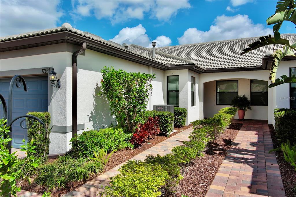A single-story house exterior features a brick walkway, manicured landscaping, and a tiled roof — 17631 CAMDEN DRIVE, BRADENTON, FL