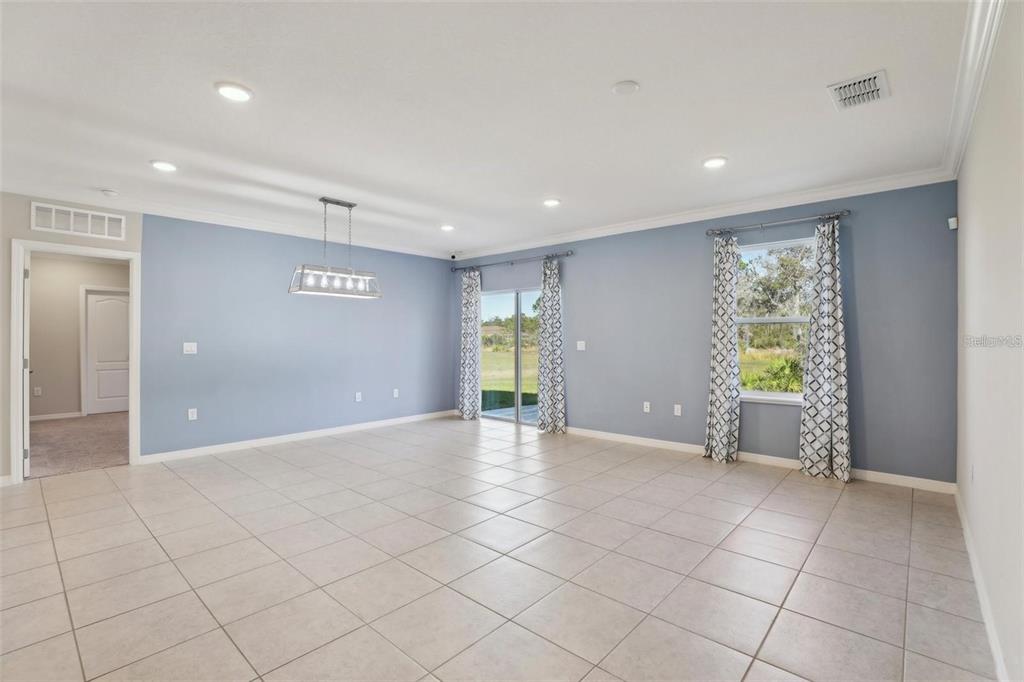 A spacious, light-blue living room features tile flooring, recessed lighting, and a sliding glass door — 2410 PARK AVENUE, INDIAN LAKE ESTATES, FL