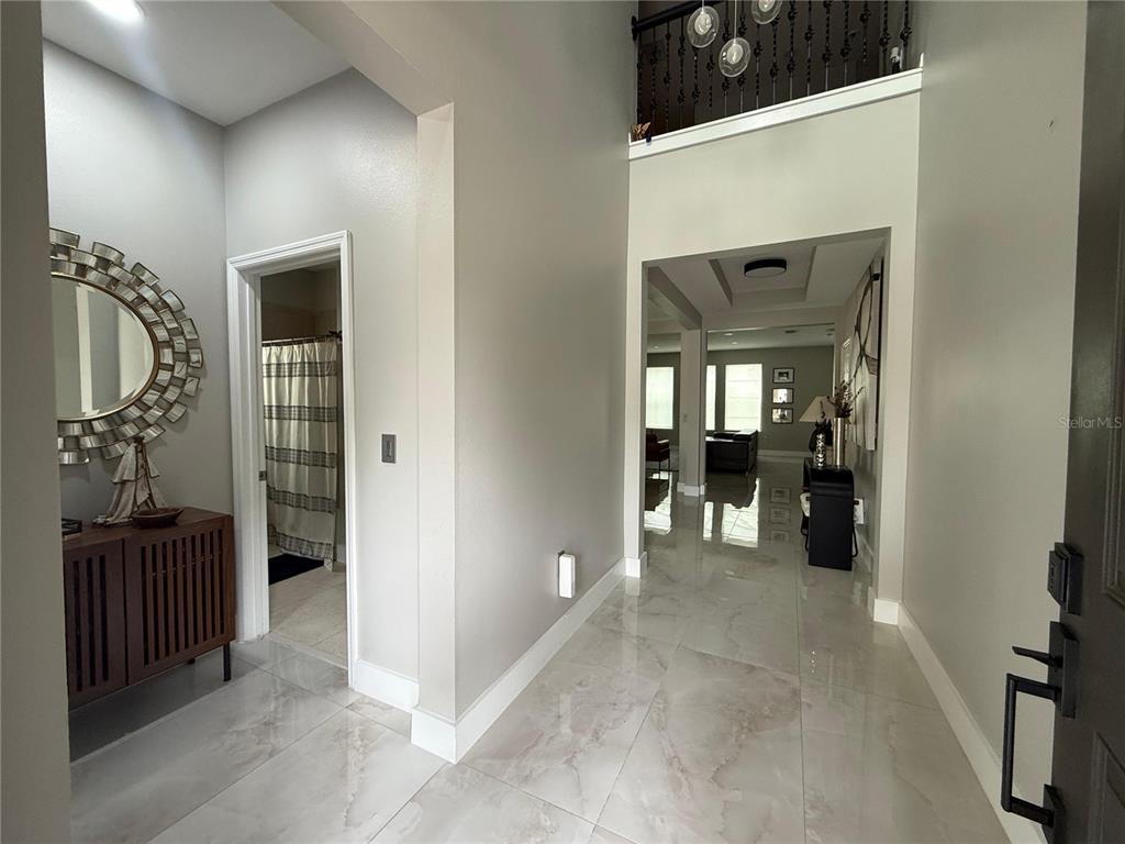 A bright foyer features light-colored marble tile flooring, a wooden console table, and a mirror — 9150 OUTLOOK ROCK TRAIL, WINDERMERE, FL