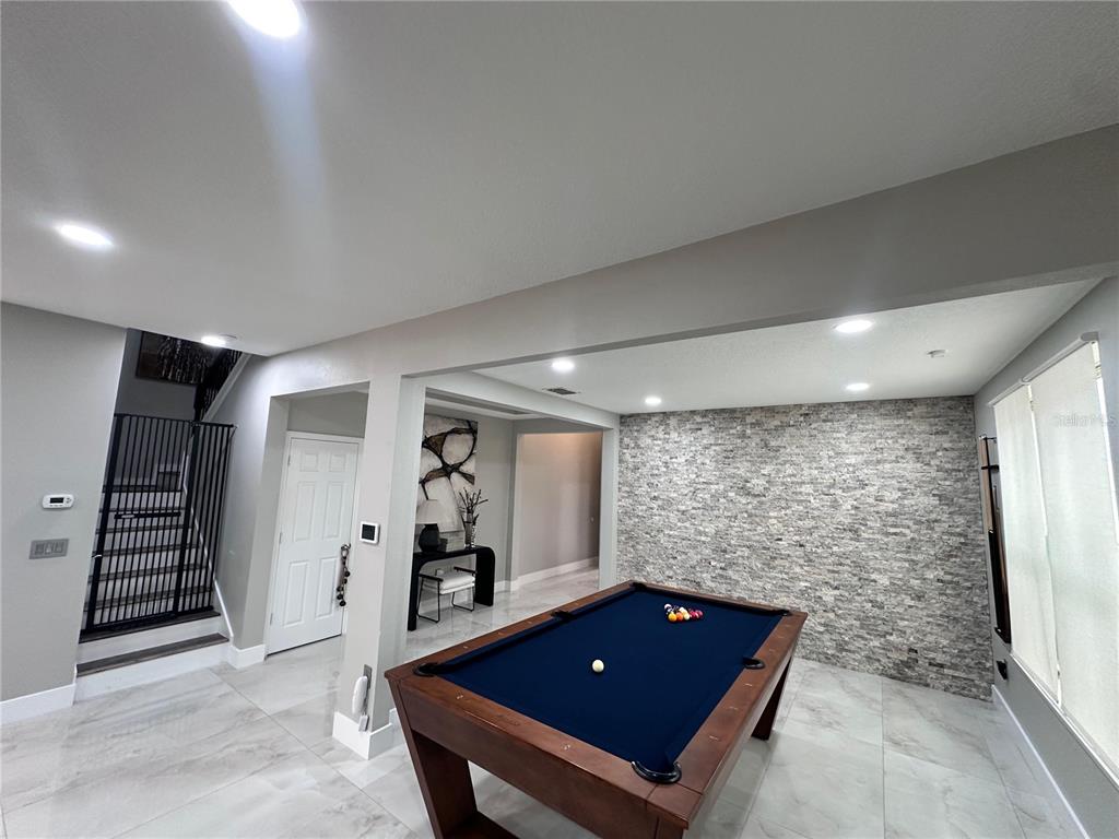 A game room features a pool table, stone accent wall, and light-colored tile flooring — 9150 OUTLOOK ROCK TRAIL, WINDERMERE, FL